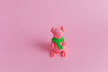 El hamuru domuz ile yeşil fular yapımı pembe Kağıt arka plan üzerinde olduğunu. Çin yeni yılı ve Çin tatil kavramı sembolü.