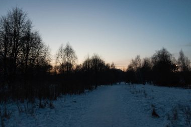 Geç akşam açık bir kasabada kışın. Cadde ve Park ile beyaz kar kaplıdır. Güneş ışığı sıcak ve son derece güzel.