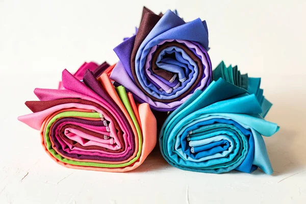 Colorful fabric swatches rolled up on white background.