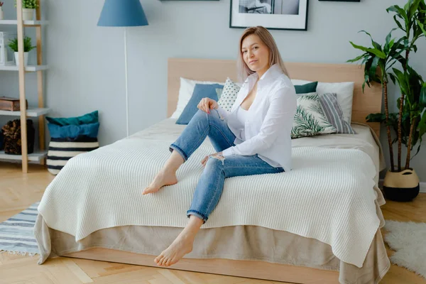 Una mujer está sentada en la cama grande — Foto de Stock