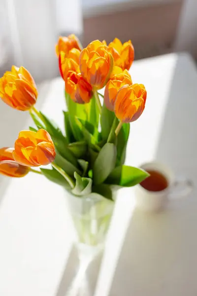 Tulipanes naranja primavera en un jarrón cerca de la ventana —  Fotos de Stock