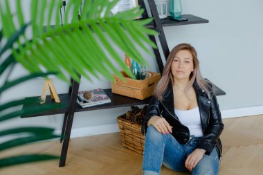 Siyah deri ceket bir sarışın kadın oturuyor