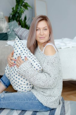 Gri pullover sarışın genç kadın yatağın yakınında