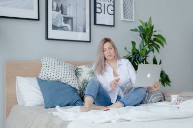 Yatakta dizüstü bilgisayar ile Sarışın genç kadın