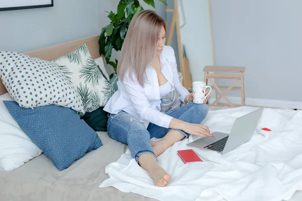 Blonde fiatal nő ül az ágyban-val laptop — Stock Fotó