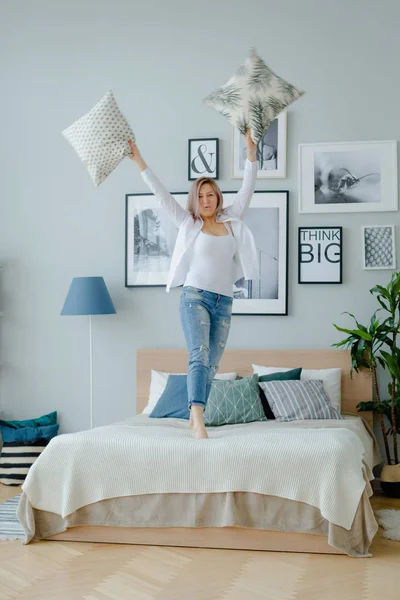 Una mujer rubia está saltando en la cama — Foto de Stock