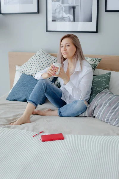 Sarışın bir kadın yatakta oturuyor