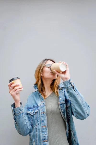 Szőke lány papír csésze kávét szürke — Stock Fotó