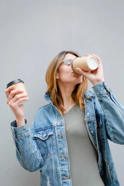 Menina loira com xícaras de papel de café em cinza — Fotografia de Stock