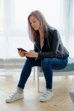 Siyah deri ceket bir sarışın kadın oturuyor