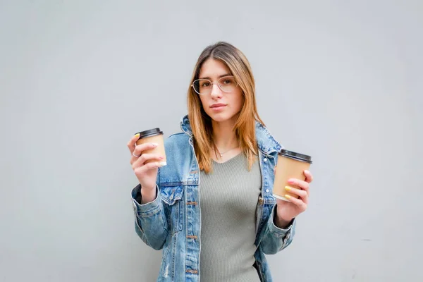 Menina loira com xícaras de papel de café em cinza — Fotografia de Stock