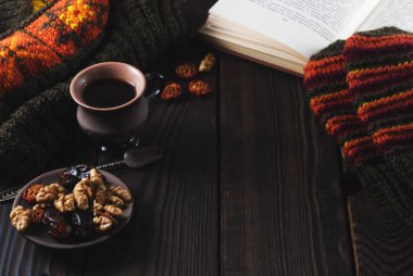 Fincan kahve, kitap, örgü şapka ve ahşap bir masa mittens