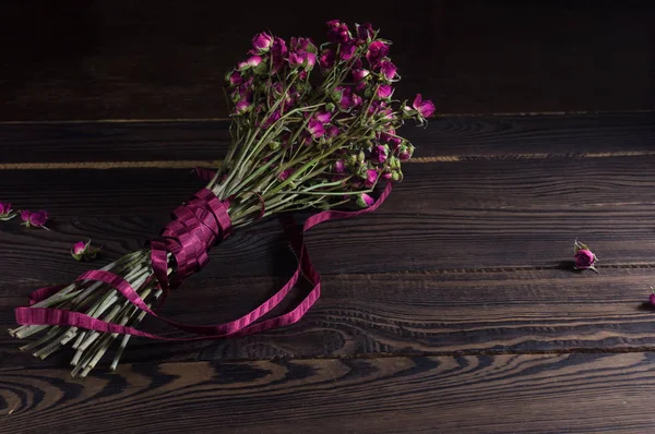 Bouquet of dry flowers with a ribbon on the dark wooden surface