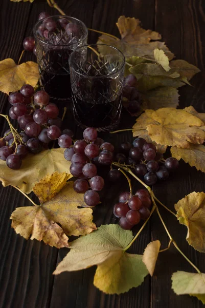 Два Хрусталя Красным Вином Виноград Сухие Листья Деревянной Поверхности — стоковое фото