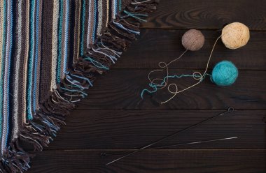 El yapımı örme kumaş, örgü iğne ve iplik koyu ahşap yüzeyde topları parçası