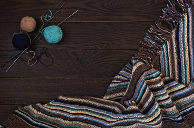 El yapımı örme kumaş, örgü iğne ve iplik koyu ahşap yüzeyde topları parçası