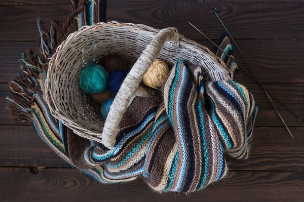 在木制表面上的柳条篮编织毛线围巾和纱线球 — 图库照片