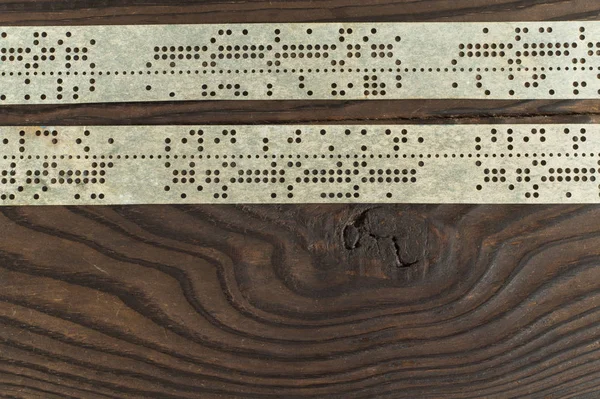 Strips of old punched tape on dark wooden surface