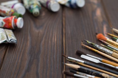 Fırçalar ve boya koyu ahşap yüzeye yayılmış