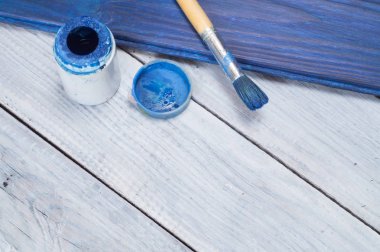 Mavi boya ve fırça beyaz tahtalar arka plan üzerinde