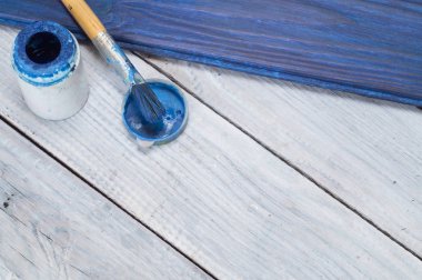 Mavi boya ve fırça beyaz tahtalar arka plan üzerinde