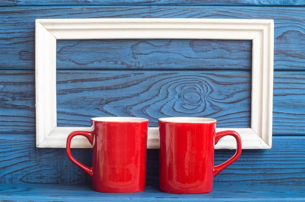 Beyaz bir çerçeve ve iki kırmızı kahve fincan bir zemin üzerine mavi panoları
