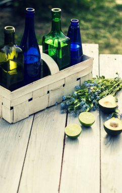 Meşrubat içinde beyaz bir sepet ve meyve beyaz masada dört şişe