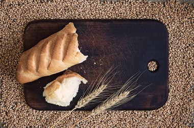 Kırık ekmek ve bir mutfak tahta arka plan buğday tanelerinin karşı kulaklara