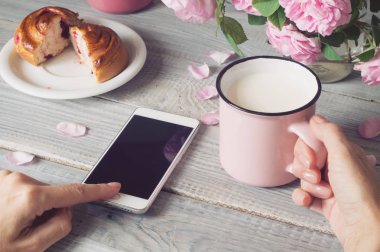 Fincan süt ve elinde bir telefon