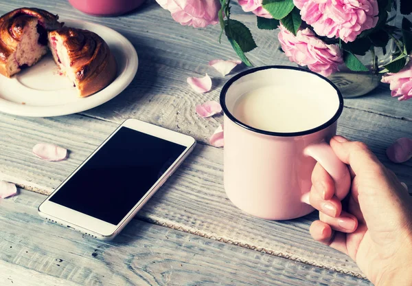 Bardak süt bir el ve bir telefon tablo