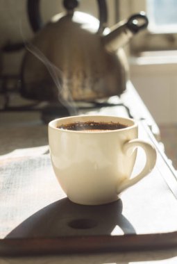 Bir fincan kahve ve arka planda çaydanlık