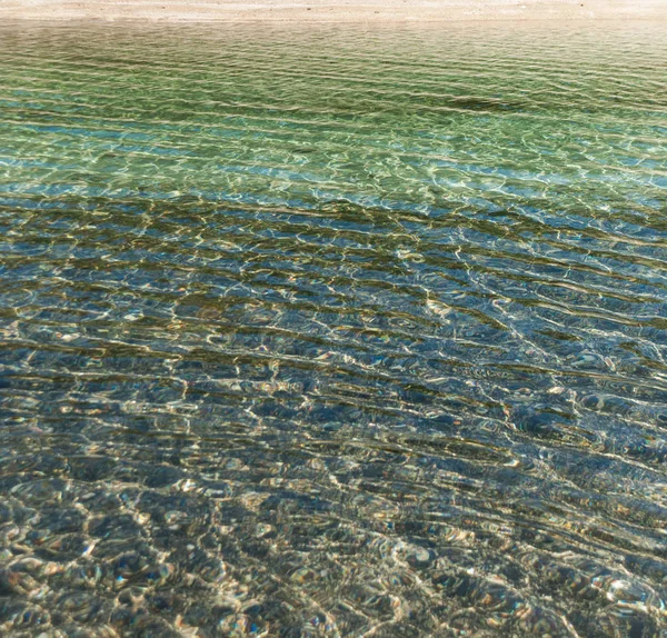 在有小浪的清澈水中折射光线 — 图库照片