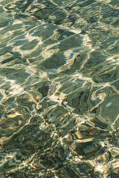 Refraction of light in clear water with small waves. Toned photo