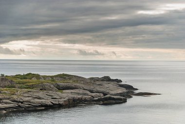 Bulutlu gökyüzü, Lofoten Adalar, Norveç bir arka plan üzerinde kayalık cape