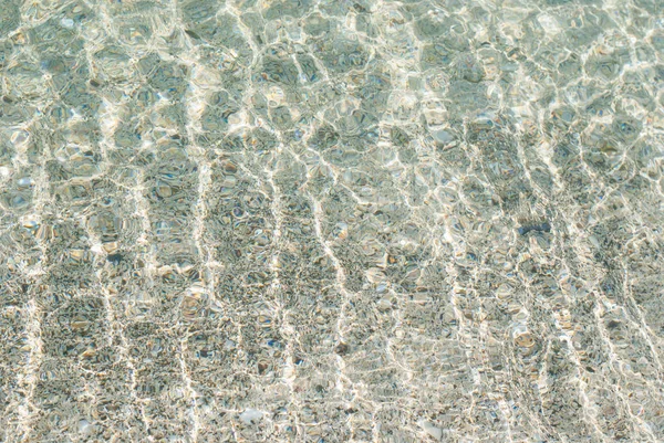 在有小浪的清澈水中折射光线 — 图库照片