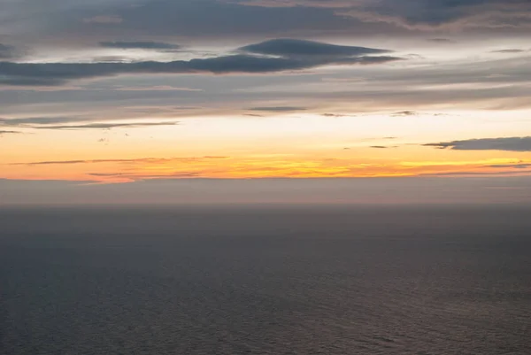 Nubes grises y anaranjadas al atardecer sobre el mar gris — Foto de Stock