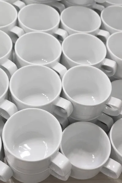Um monte de copos de porcelana branca vazia em uma mesa — Fotografia de Stock