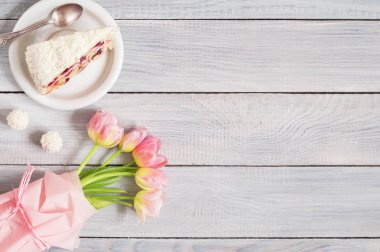 Beyaz ahşap masada kiraz ve pembe lale ile bir pasta