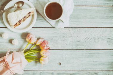 Beyaz ahşap masada kiraz, çay ve pembe lale fincan ile bir pasta