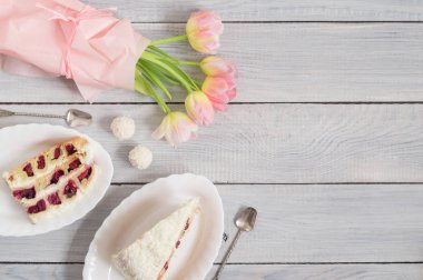 Beyaz ahşap masada kiraz ve pembe lale ile bir pasta