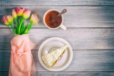 Beyaz ahşap masada kiraz, çay ve pembe lale fincan ile bir pasta