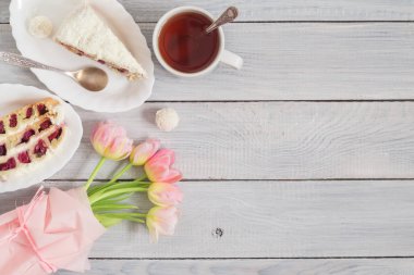 Kiraz, çay ve pembe lale beyaz ahşap bir fincan bir pasta