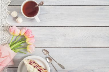 Kiraz, çay ve pembe lale beyaz ahşap bir fincan bir pasta
