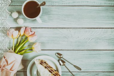 Kiraz, çay ve pembe lale beyaz ahşap bir fincan bir pasta