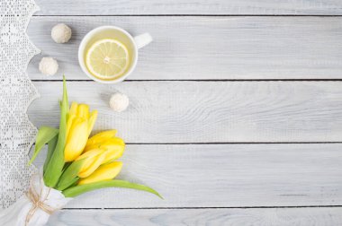 Sarı laleler, limon çayı ve şekerler beyaz ahşap masa
