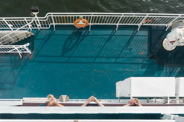 Manos de hombre sosteniendo copas de vino en una cubierta de barco — Foto de Stock
