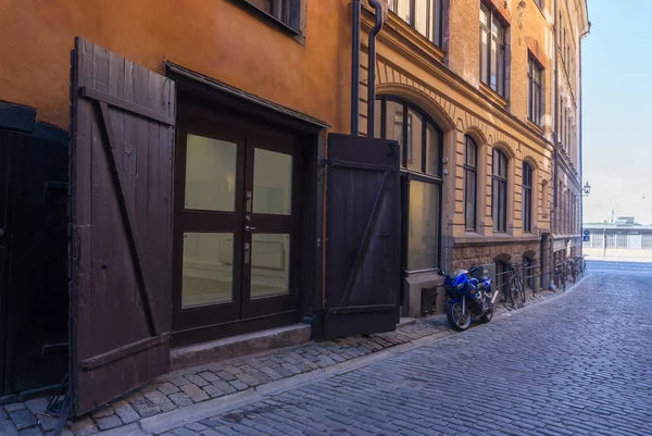 Motocykl a dřevěná brána na staré městské ulici ve Stockholmu, — Stock fotografie