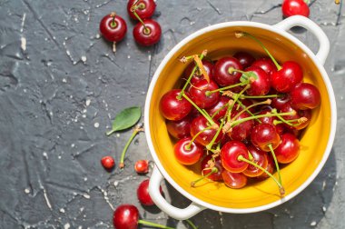 Koyu bir arka plan üzerinde seramik bir kapta Kiraz