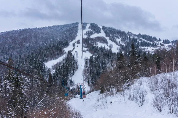 Narciarze na wyciągu narciarskim na zboczu góry — Zdjęcie stockowe