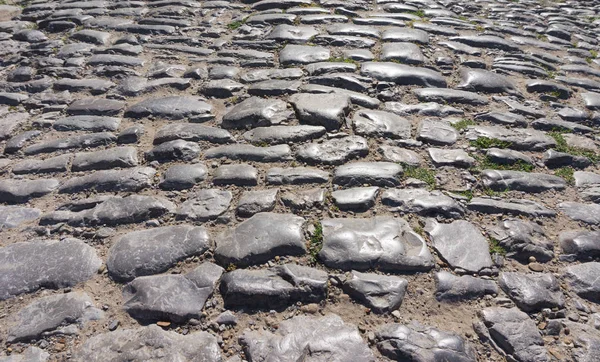 Gamla stenar på asfalterad väg — Stockfoto